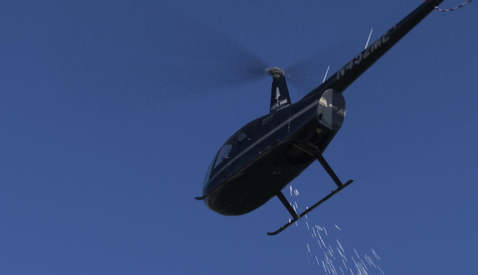 In this photo made from video, a helicopter drops marshmallows to a park below in Southfield, Mich., on Friday, March 29, 2024. The annual Great Marshmallow Drop took place at Catalpa Oaks County Park in Southfield, Michigan, and was hosted by Oakland County Parks. (AP Photo/Mike Householder)