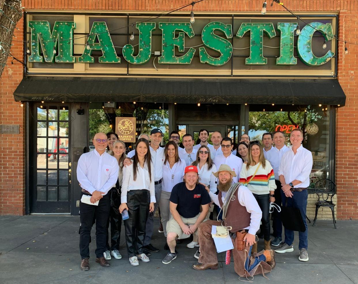 A Downtown Abilene Walking Tour group snaps a photo outside the Majestic coffee shop on Pine Street with their cowboy poet tour guide 'Gus McDusty.'