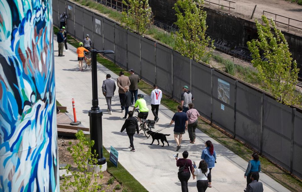 People walk their dogs and ride their bikes during the grand opening of the Southwest Greenway in Detroit on Wednesday, May 24, 2023. The Southwest Greenway is a pedestrian pathway part of the 27.5-mile Joe Louis Greenway that connects the Detroit Riverfront to Michigan Central and surrounding neighborhoods.