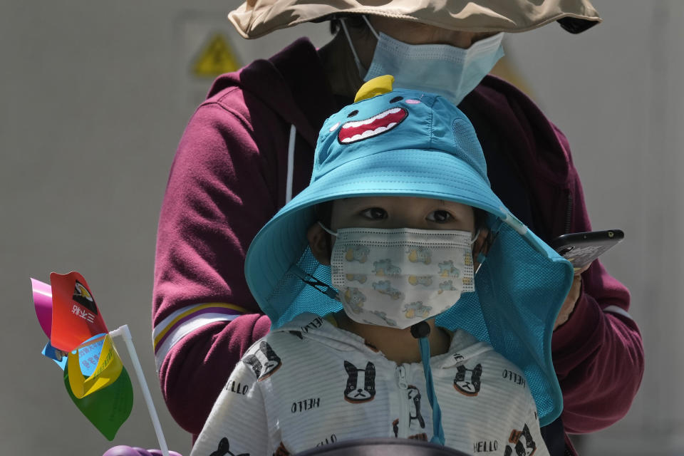 A child wearing a mask waits outside a COVID mass testing site on Sunday, May 15, 2022, in Beijing. (AP Photo/Ng Han Guan)