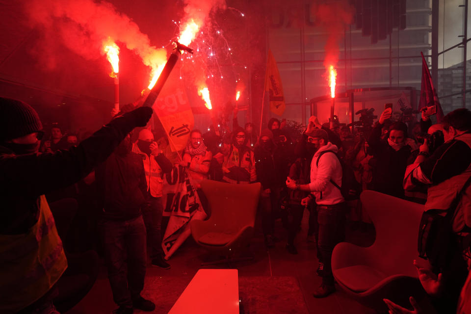 Demonstrators holding flares invading the Euronext Paris building in protest to the pension reforms at La Defense business district in Paris, Thursday, April 20, 2023. Union activists stage scattered actions to press France's government to scrap the new law raising the retirement age. (AP Photo/Thibault Camus)