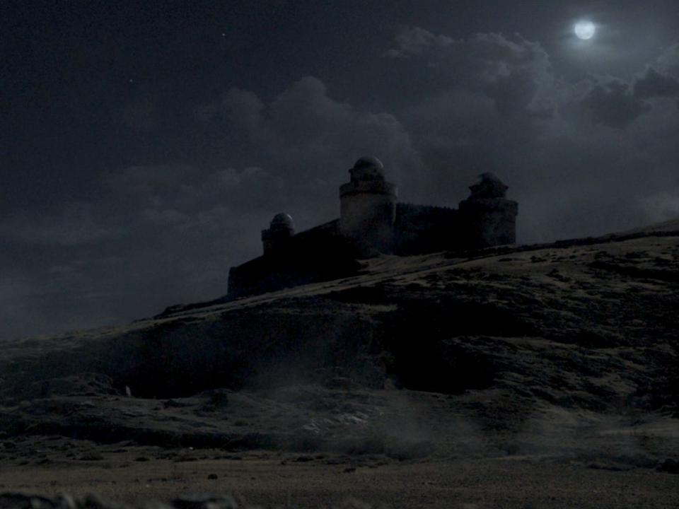 A scene from "House of the Dragon," showing a castle on a hill in the moonlight.