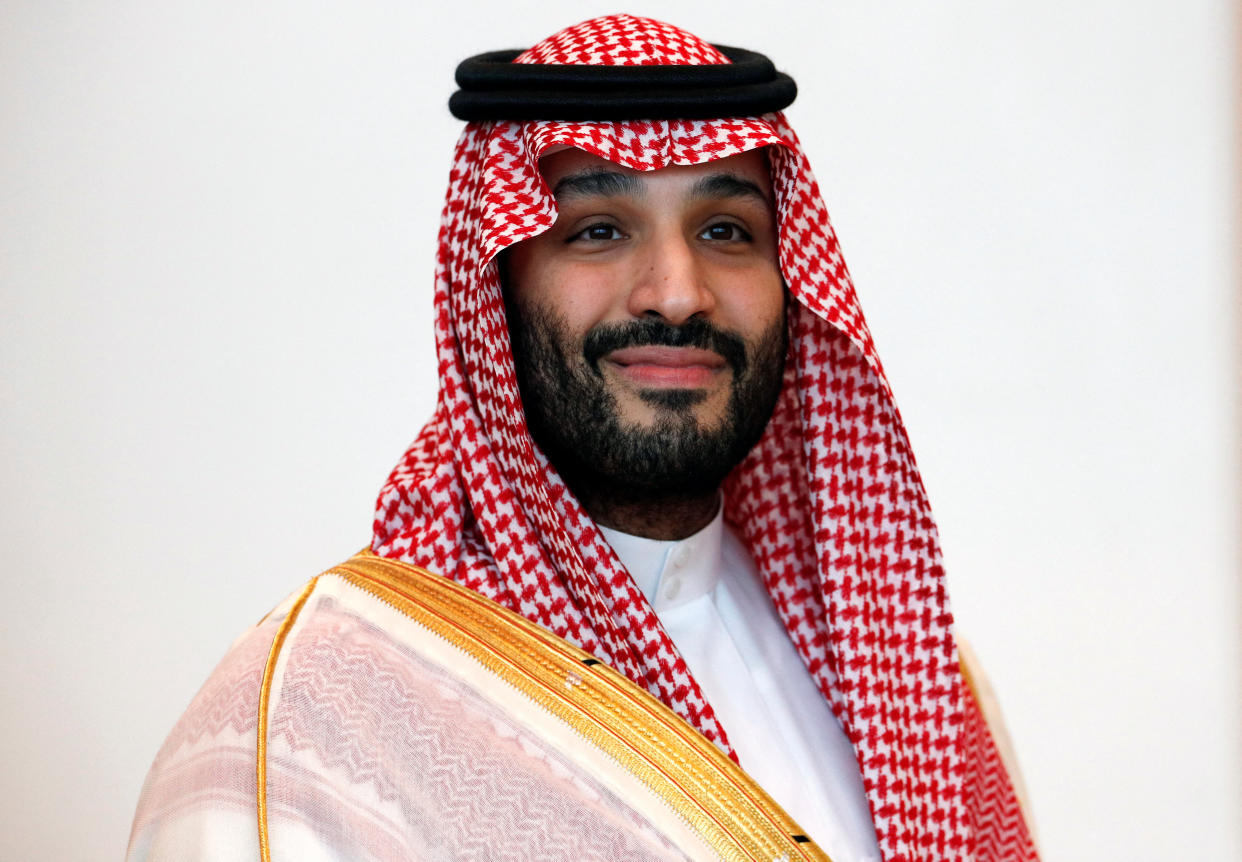Crown Prince Mohammed bin Salman, in dishdasha attire, with red and white checked headdress and white robe with gold trim.
