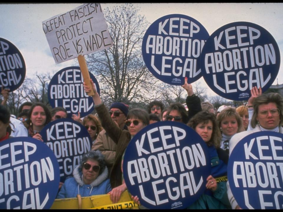 Demonstrators carrying giant keep abortion legal buttons & ...protect Roe vs. Wade sign during huge pro-choice march. (