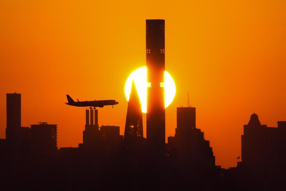 The sun sets behind the Manhattan skyline as a plane approaches for a landing at LaGuardia Airport in New York on Sept. 6, 2023. (AP Photo/Frank Franklin II)