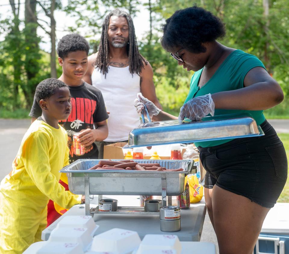Amiracle Tolbert serves hots dogs with Terrance Jones first in line    Saturday at the back-to-school event at King Kennedy Community Center in Ravenna.