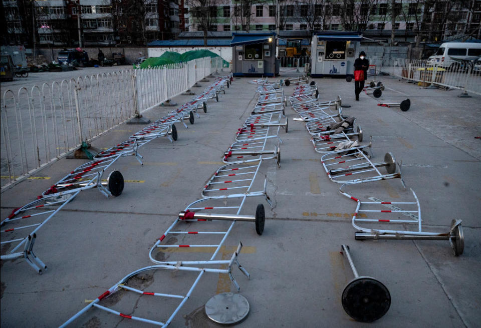 A woman walks by barricades as they are seen scattered on the ground at a testing site for COVID-19, on Dec. 19, 2022 in Beijing, China.<span class="copyright">Kevin Frayer—Getty Images</span>