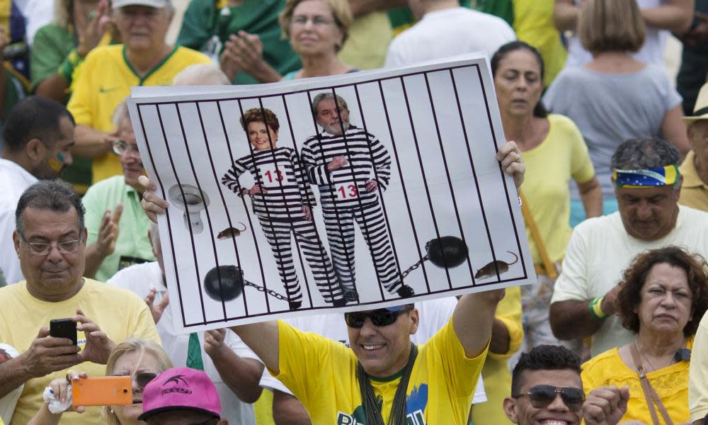 An anti-corruption protester holds a poster with Dilma Rousseff and Lula in prison stripes. 