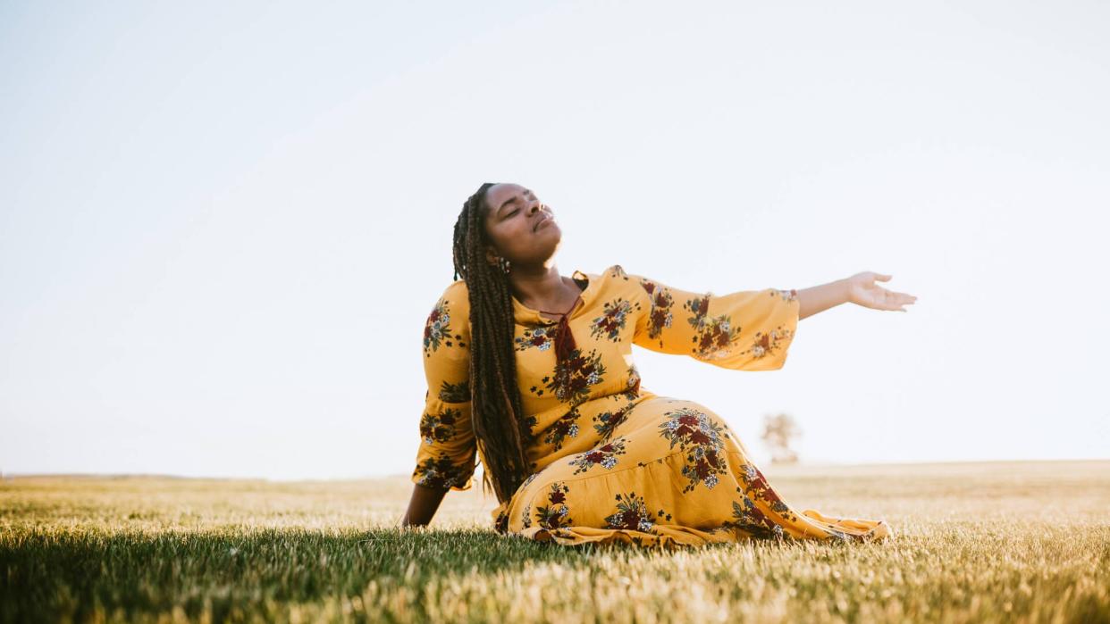 A beautiful young adult African woman enjoys the beauty of the summer , her eyes closed in prayer, worship, or meditation.