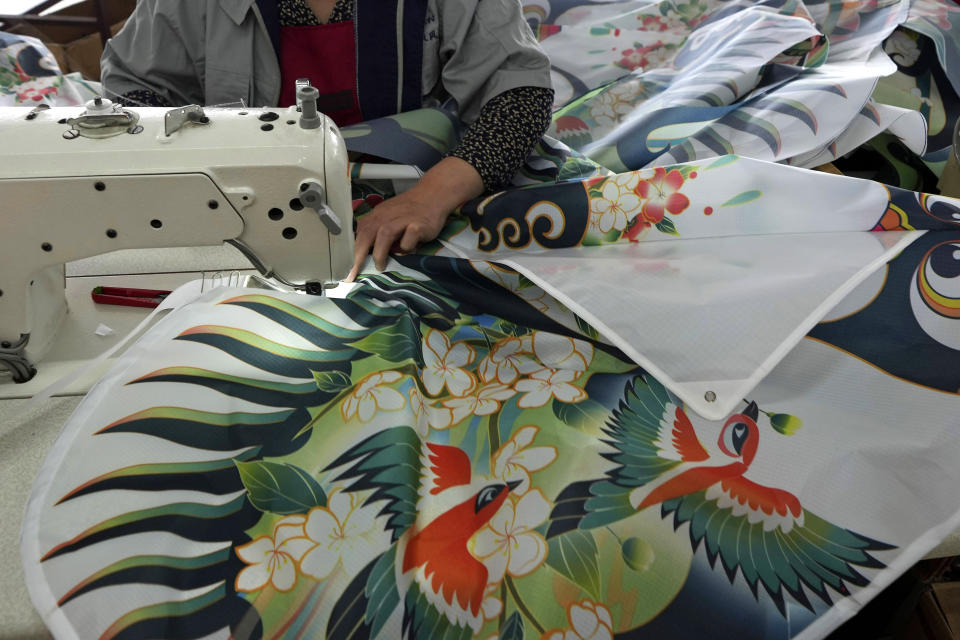 Workers stitch kites at a workshop in Weifang, Shandong Province of China, Friday, April 19, 2024. (AP Photo/Tatan Syuflana)