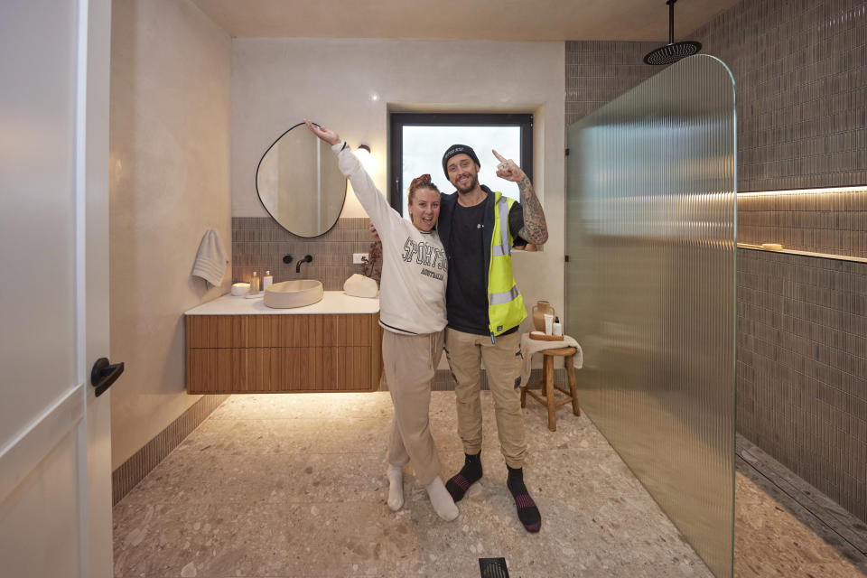 Kristy and Brett smile and pose in front of their vanity. 