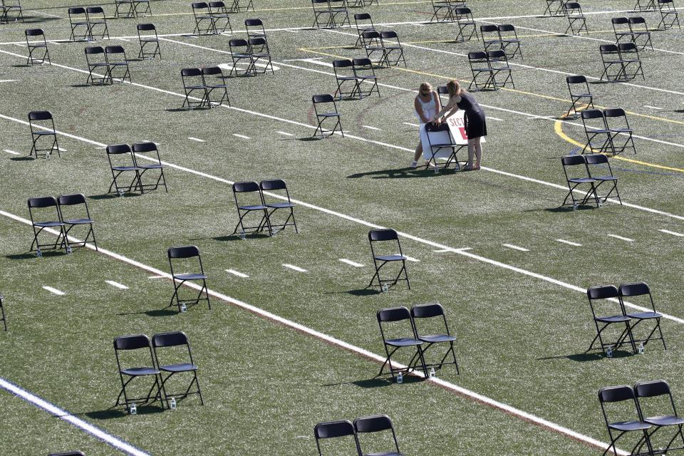 Two women help to prepare the North Andover high school football field for social distancing due to COVID-19 virus concerns, prior to the annual town meeting, Tuesday, June 16, 2020, in North Andover, Mass. It is the first ever outdoor town meeting since North Andover was established in 1646. (AP Photo/Elise Amendola)
