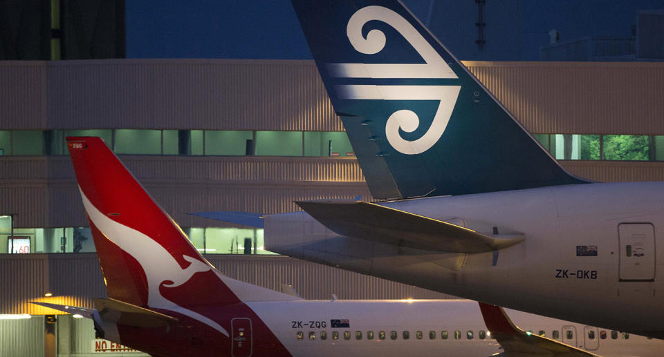 The tails of a Qantas plane and an Air New Zealand plane are seen parked at a gate.