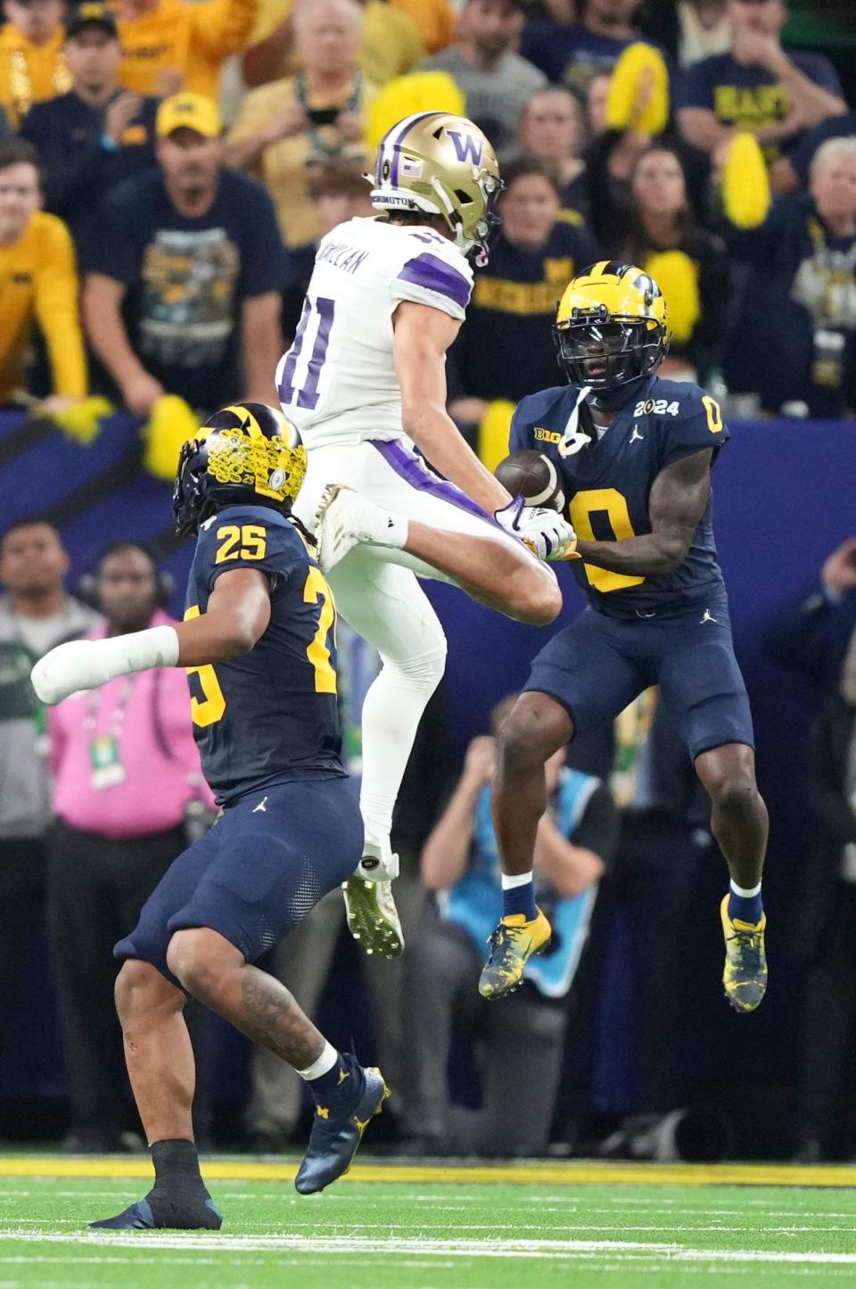 Michigan defensive back Mike Sainristil (0) intercepts a ball meant for Washington wide receiver Jalen McMillan (11) during the fourth quarter of the College Football Playoff national championship game against Washington at NRG Stadium in Houston, Texas on Monday, January 8, 2024.