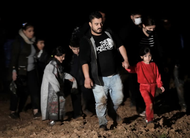 Detained migrants walk next to the Belarus-Latvia border near Vorzova