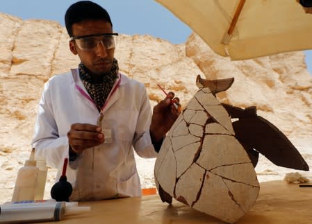 An Egyptian archaeologist works on objects discovered through an archaeological mission in the Monkey Valley near the Valley of the Kings in Luxor