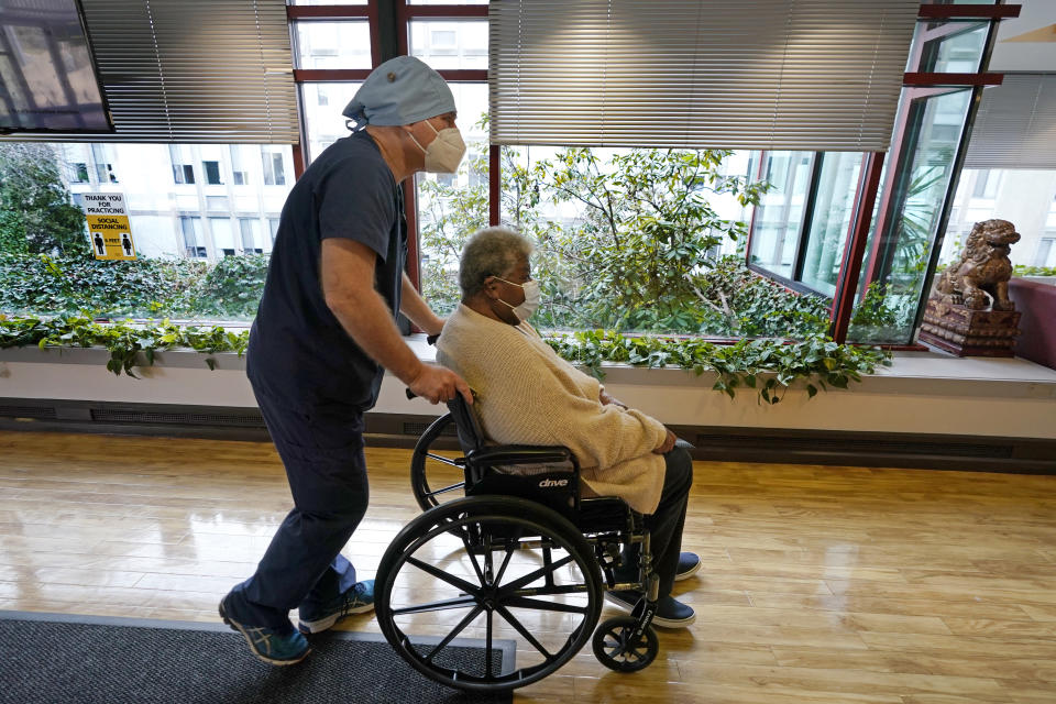 Patricia Marson is wheeled back to her room by nurse manager Rob Treiber after she became the first patient at Hebrew Rehabilitation Center to receive a COVID-19 vaccine, Wednesday, Dec. 30, 2020, in Boston. (AP Photo/Elise Amendola)