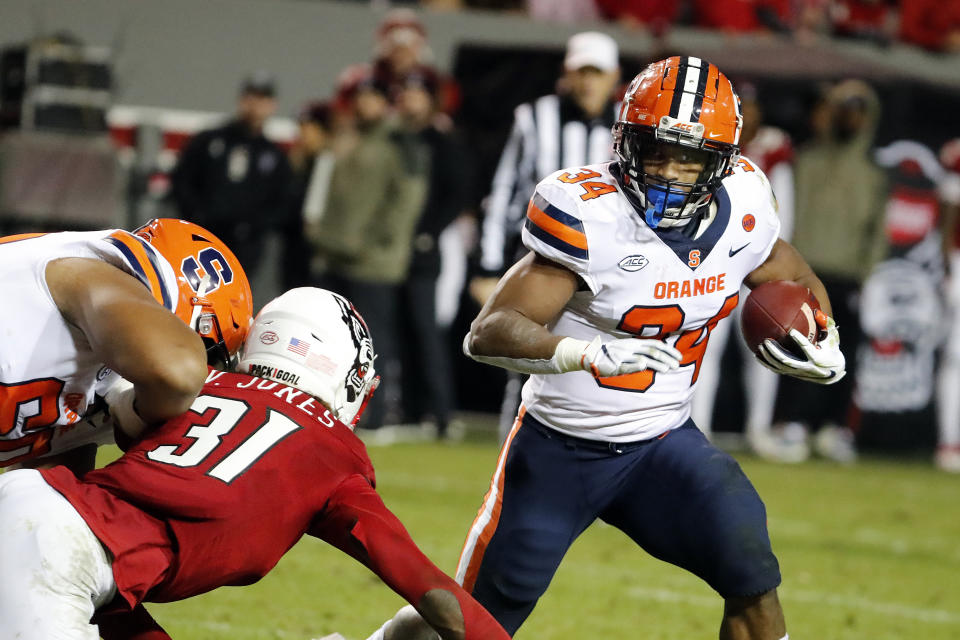 FILE - Syracuse's Sean Tucker (34) runs the ball around North Carolina State's Vi Jones (31) during the second half of an NCAA college football game in Raleigh, N.C., Saturday, Nov. 20, 2021. Syracuse is set to kick off its season on Sept. 3, 2022, against Louisville. (AP Photo/Karl B DeBlaker, File)