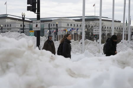 People make their way through piles of plowed snow in Washington January 26, 2016. REUTERS/Jonathan Ernst