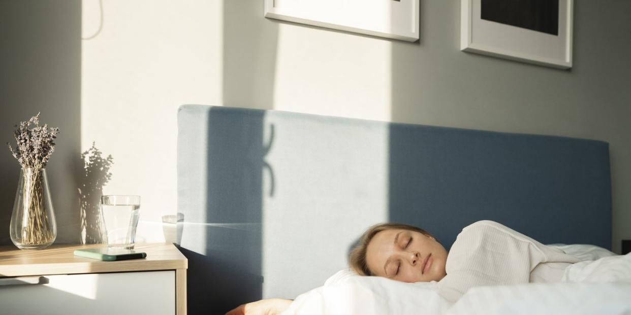 young woman sleeping in bed by table at home