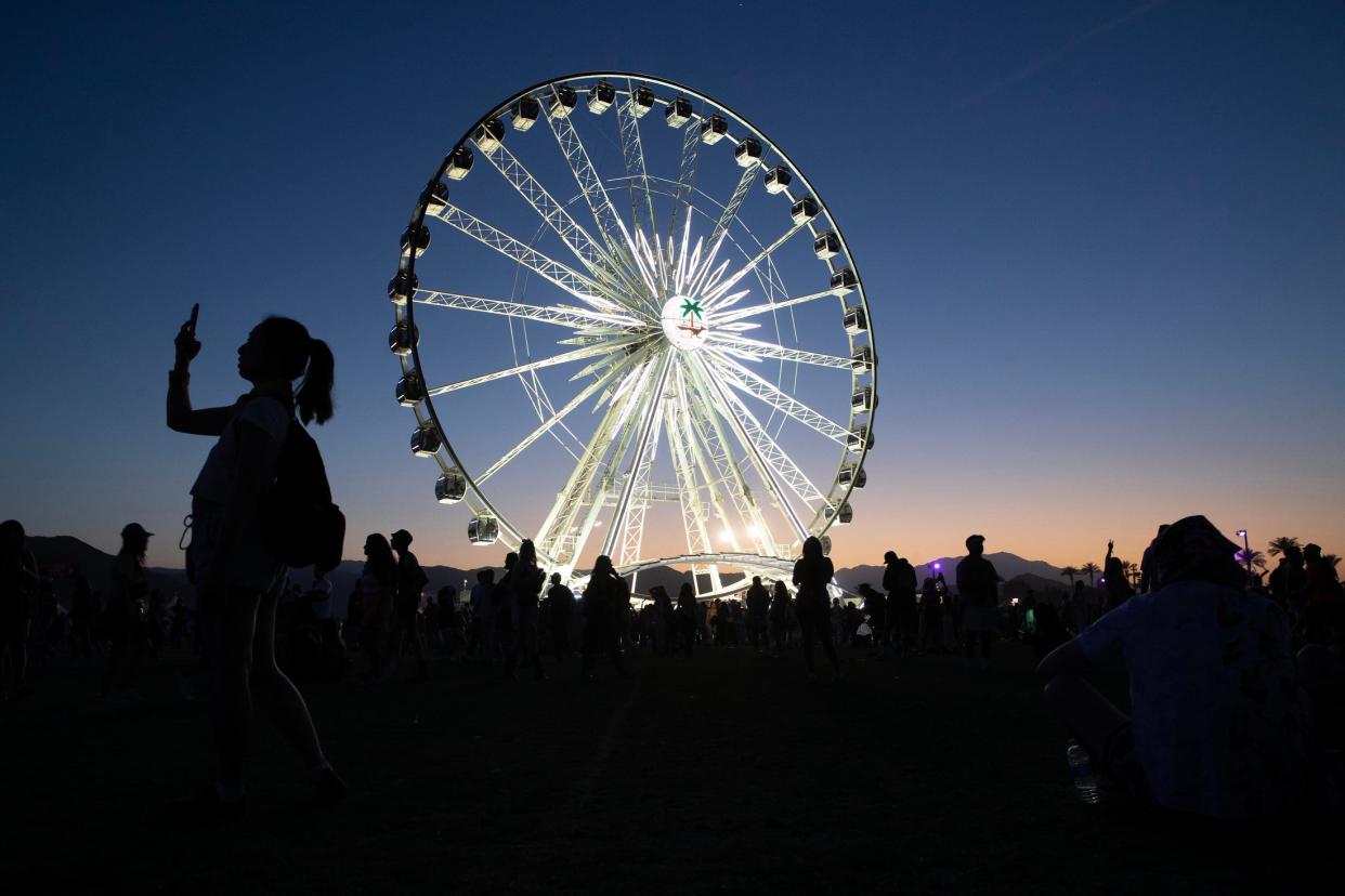 A person takes a selfie at dusk near the Ferris wheel during the Coachella Valley Music and Arts Festival in Indio, Calif., on Sunday, April 16, 2023. 