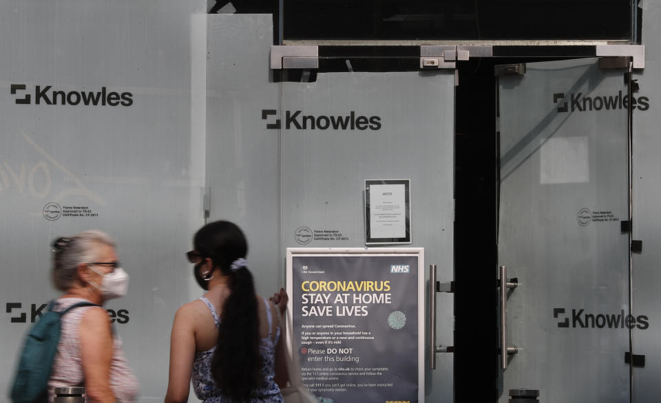 Two women stand outside a closed branch of a shoe shop in Kensington, London, Wednesday, Aug. 12, 2020. The British economy is on course to record the deepest coronavirus-related slump among the world's seven leading industrial economies after official figures showed it shrinking by a 20.4% in the second quarter of 2020 alone said The Office for National Statistics. (AP Photo/Alastair Grant)