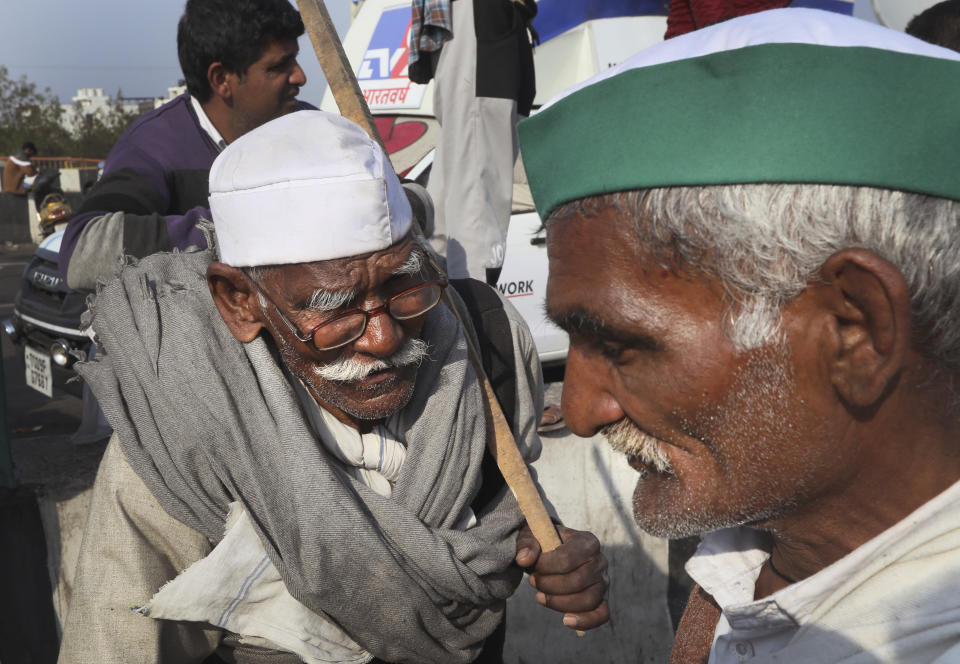 Elderly farmers talk on a heavily barricaded road along one of the three main protest sites outside New Delhi's border to thwart the growing farmers' protest on the edges of the capital, at Delhi-Uttar Pradesh border, in New Delhi, India, Friday, Feb. 5, 2021. India's agriculture minister on Friday defended the new agriculture reform laws in Parliament, dampening hopes of any quick settlement with tens of thousands of protesting farmers demanding their repeal by blocking three highways connecting New Delhi to northern India for over two months now. (AP Photo/Manish Swarup)