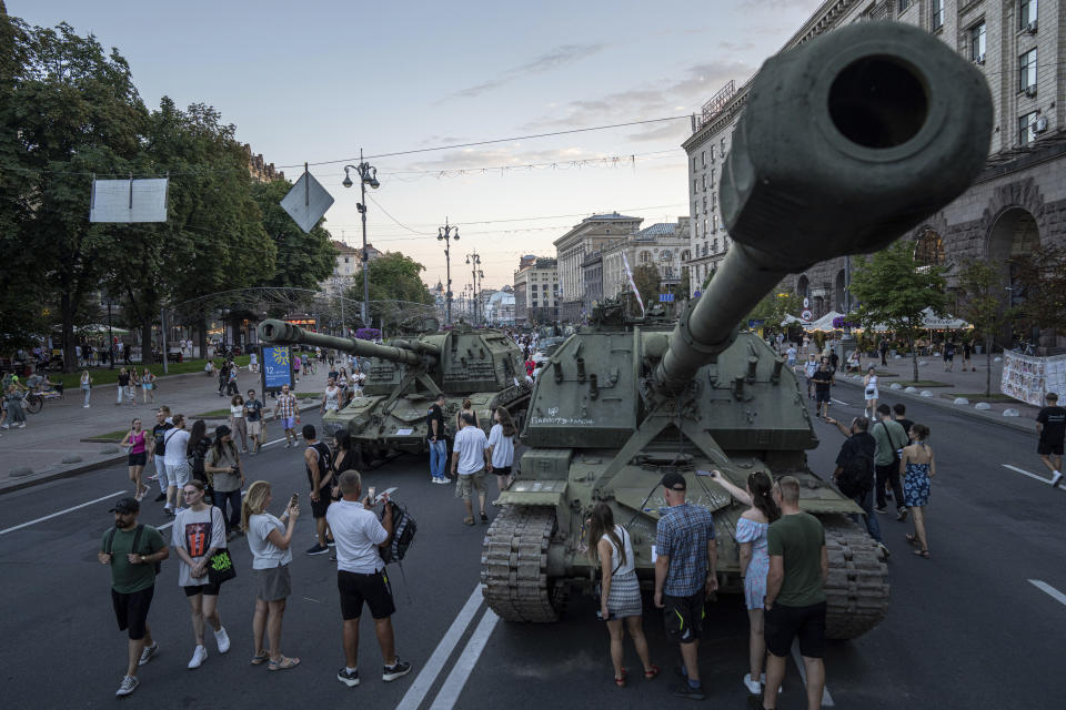 People walk in front of destroyed Russian artillery vehicles installed on Khreschatyk street in downtown of Kyiv, Ukraine, Saturday, Aug. 26, 2023. (AP Photo/Evgeniy Maloletka)