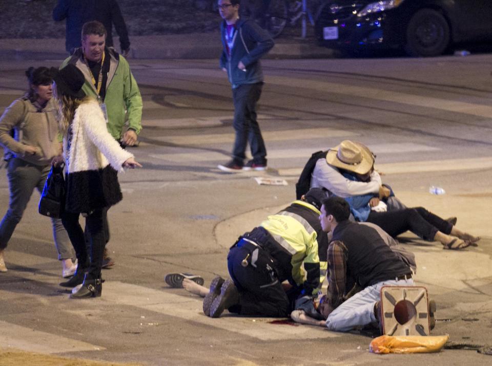 People perform CPR on a woman after she was struck by a vehicle on Red River Street in downtown Austin, Texas, at SXSW on Wednesday March 12, 2014. Police say a man and woman have been killed after a suspected drunken driver fleeing from arrest crashed through barricades set up for the South By Southwest festival and struck the pair and others on a crowded street. (AP Photo/Austin American-Statesman, Jay Janner)