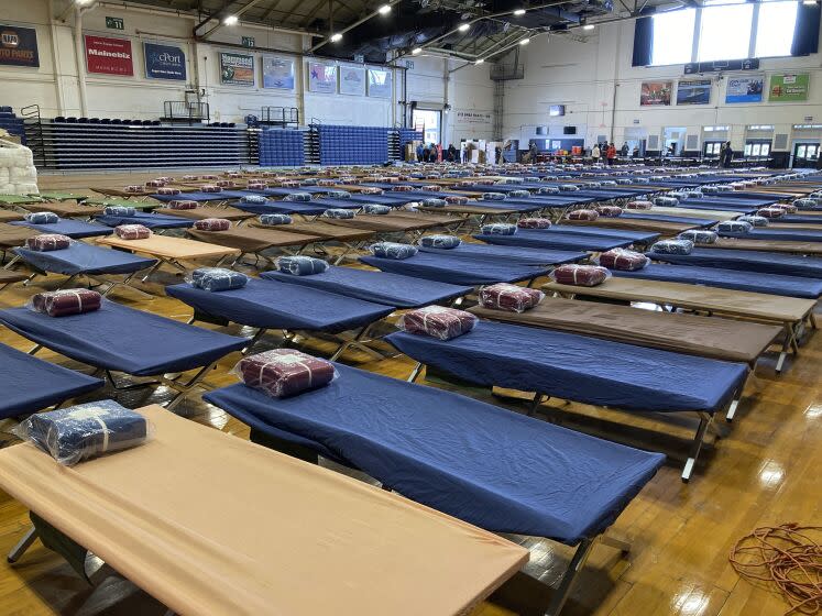 Cots are arranged on the floor of the Portland Expo Center, Friday, April 7, 2023, in Portland, Maine. The state is reopening a basketball arena for immigrants following the arrival of more than 800 asylums seekers since the beginning of the year. (AP Photo/David Sharp)