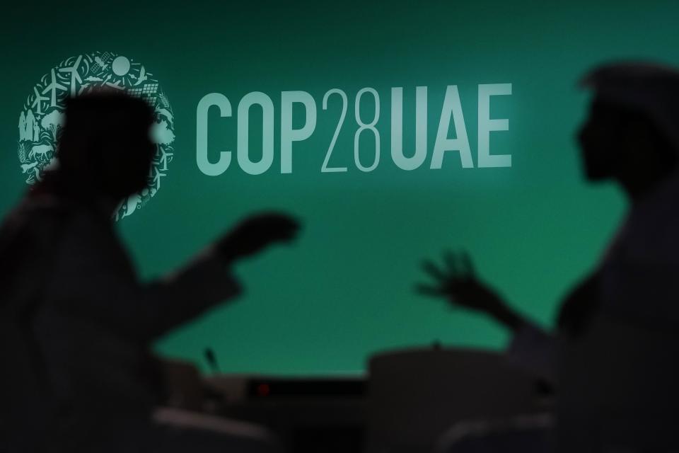 FILE - People are silhouetted against a logo for the COP28 U.N. Climate Summit, Nov. 29, 2023, in Dubai, United Arab Emirates. (AP Photo/Rafiq Maqbool, File)