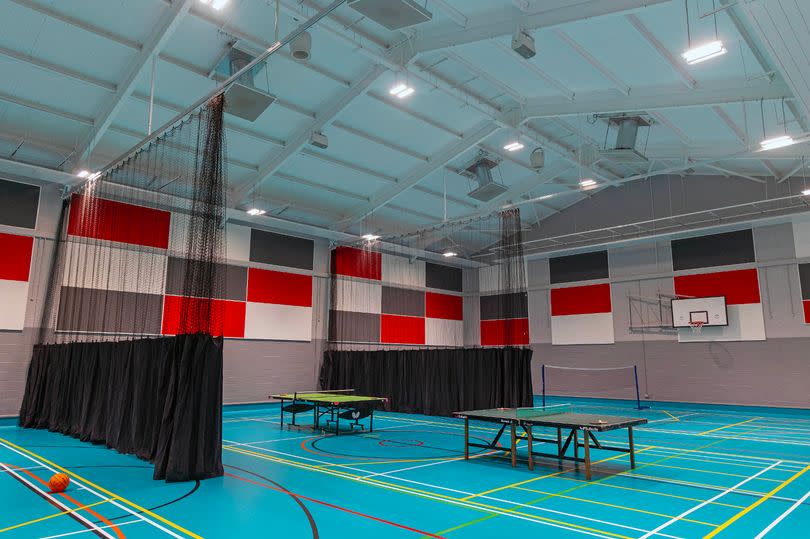 A general image of a large hall with two table tennis tables in the centre