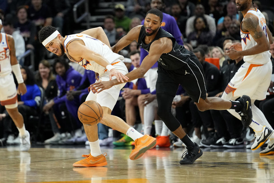 Brooklyn Nets forward Mikal Bridges, right, knocks the ball away from Phoenix Suns guard Devin Booker during the second half of an NBA basketball game, Wednesday, Dec. 13, 2023, in Phoenix. (AP Photo/Matt York)