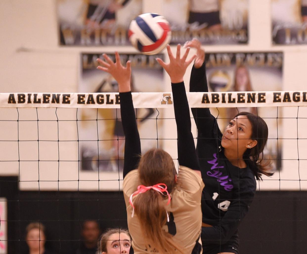 Abilene Wylie's Bri Johnston (14) hits the ball as an Abilene High player defends. Wylie beat the Lady Eagles 25-27, 25-15, 26-24, 25-21 in the District 4-5A match Tuesday, Oct. 3, 2023, at Eagle Gym.