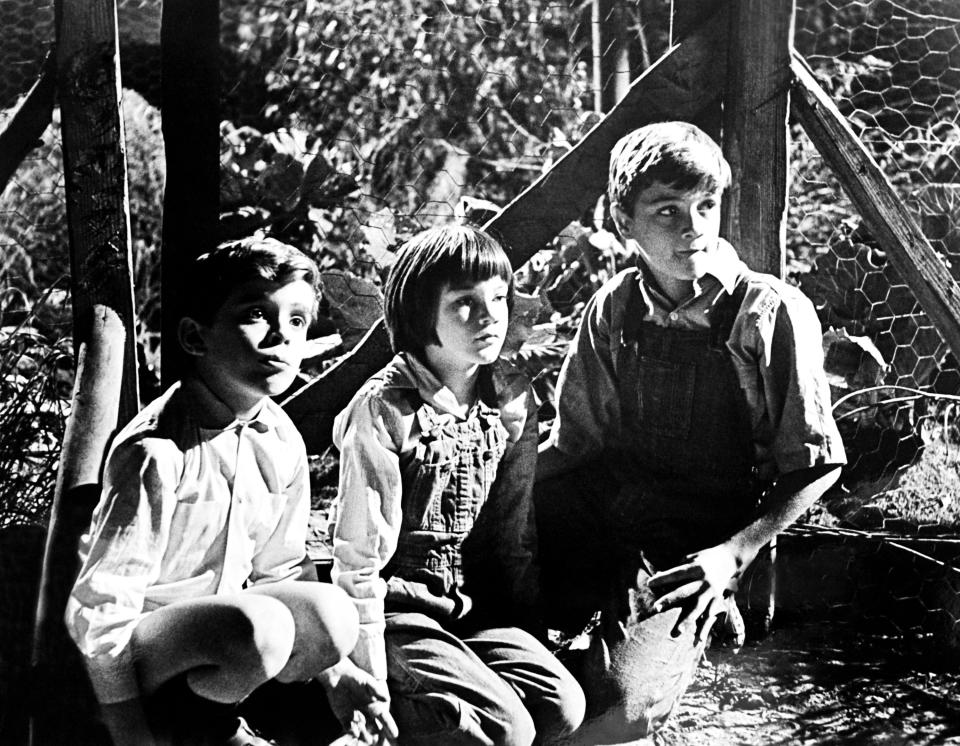 Three children sit outside in "To Kill a Mockingbird"