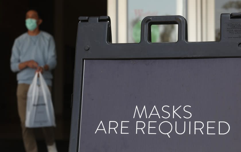 ARCADIA, CA - OCTOBER 07, 2020 - A sign tells customers to wear masks to prevent the spread of COVID-19 as shoppers return to indoor shopping at the Westfield Santa Anita shopping mall in Arcadia on October 7, 2020. This is the first day customers were allowed to return to indoor shopping after Los Angeles County eased restrictions and have reopened the malls and the individual stores. Such stores have been closed for weeks, but reopened Wednesday at 25% capacity. Westfield Santa Anita has placed Covid-related signage with one-way traffic, 6 feet distancing when waiting to get into individual stores, hand sanitizing stations and mask are required before entering the mall. (Genaro Molina / Los Angeles Times)