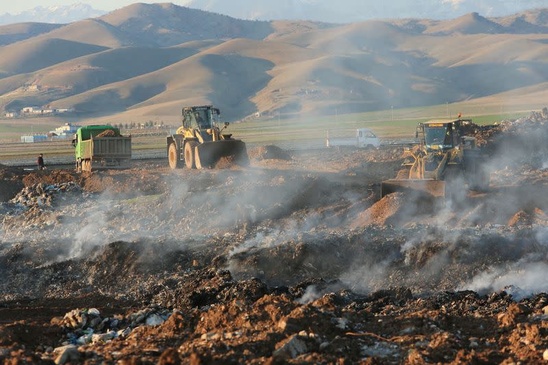 FILE PHOTO: A bulldozer carries garbage to put in an underground hole with the aim of diverting the area into a green park after it was a landfill, in Zakho, district of Dohuk