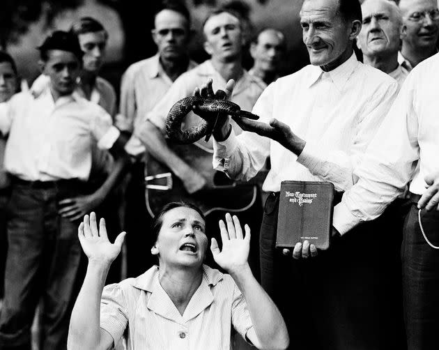Members of a faith-healing sect surround a woman as a man holds a snake above her head in Evarts, Kentucky, on Aug. 22, 1944.