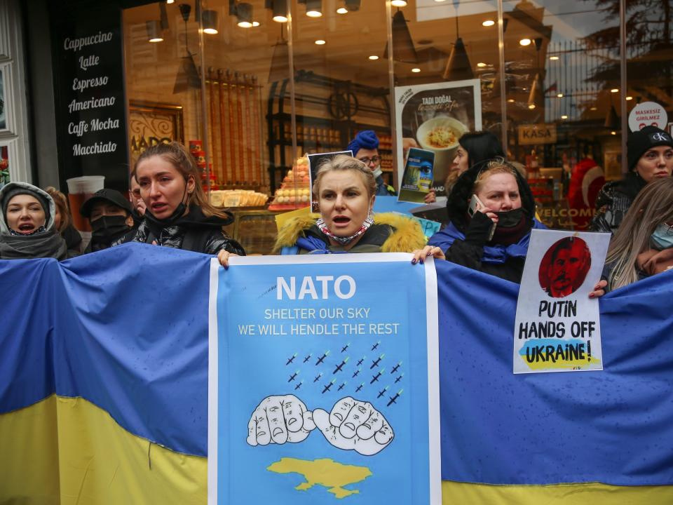 Protesters hold a sign that says "Putin hands off Ukraine"