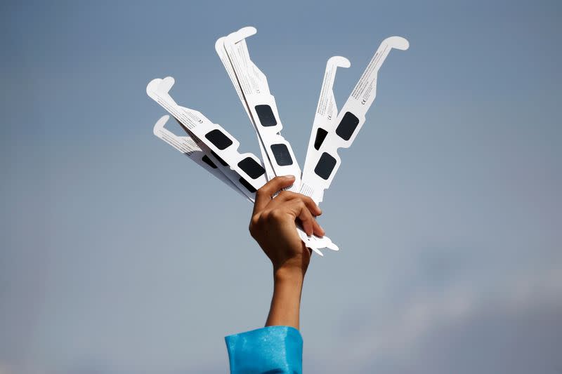 A vendor raises protective glasses for the solar eclipse in Siak