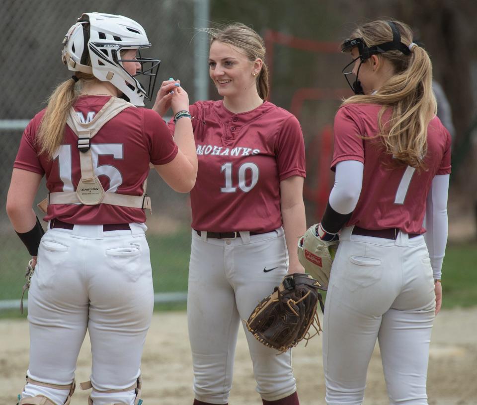 Millis High School catcher Emilia Leach, Isabelle Jewett, and pitcher Riley Caufield in between innings against Millis, April 10, 2024.