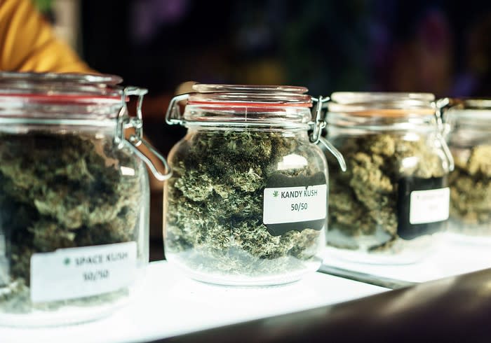 Clearly labeled jars of dried cannabis on a dispensary store counter.