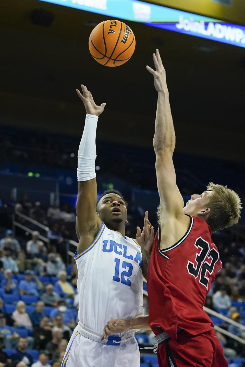 UCLA guard Sebastian Mack (12) shoots against St. Francis forward Aidan Harris (32) during the first half of an NCAA college basketball game, Monday, Nov. 6, 2023, in Los Angeles. (AP Photo/Ryan Sun)