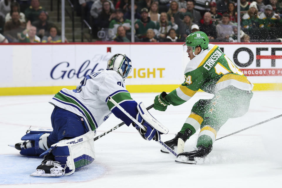 Vancouver Canucks goaltender Casey DeSmith, left, makes a save on a shot by Minnesota Wild center Joel Eriksson Ek (14) during the second period of an NHL hockey game Saturday, Dec. 16, 2023, in St Paul, Minn. (AP Photo/Matt Krohn)