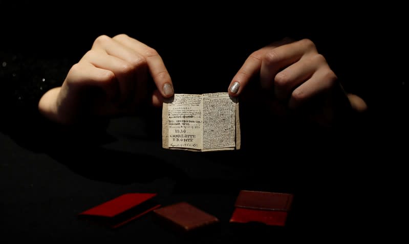 An employee displays the second issue of Young Men's Magazine, a miniature manuscript dated 1830, written by Charlotte Bronte when she was 14 years old, before being put on auction at Drouot auction house in Paris