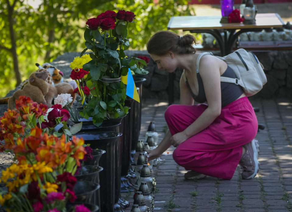 A woman lights a candle at a shopping center, after a rocket attack in Kremenchuk, Ukraine, Tuesday, June 28, 2022. (AP Photo/Efrem Lukatsky)