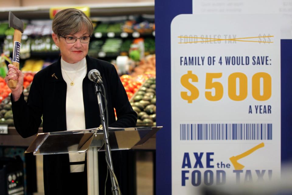 Kansas Gov. Laura Kelly raises an axe while promoting her proposal to eliminate the state's 6.5% sales tax on groceries during a news conference in the produce section of a Dillons grocery in Topeka, Kansas, on Nov. 8.