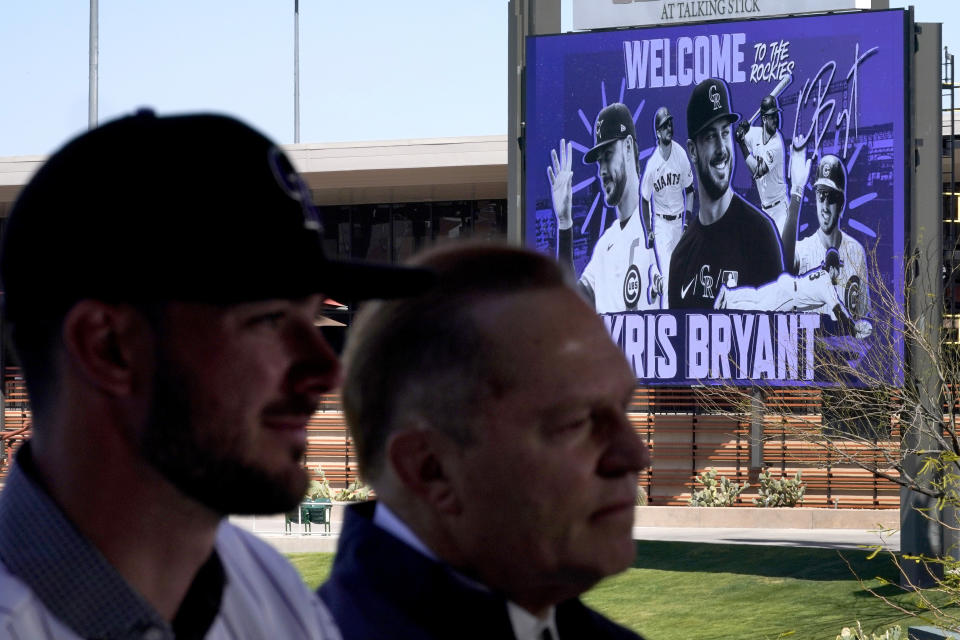 The centerfield scoreboard welcomes Colorado Rockies' Kris Bryant, left, as he an agent Scott Boras are introduced by the baseball team for the first time, Friday, March 18, 2022, in Scottsdale, Ariz. (AP Photo/Matt York)