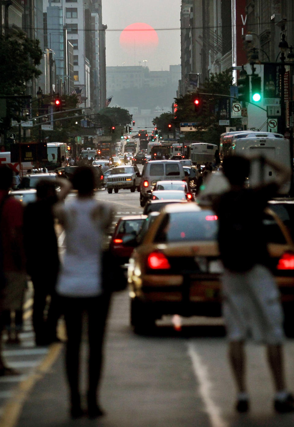 People take photographs as the sun sets on 34th Street across the west side of Manhattan, during an event known as Manhattanhenge, on May 31, 2011 in New York City. The phenomenon occurs twice yearly when the setting sun aligns perfectly with the city's east-west street grid. (Photo by Mario Tama/Getty Images)