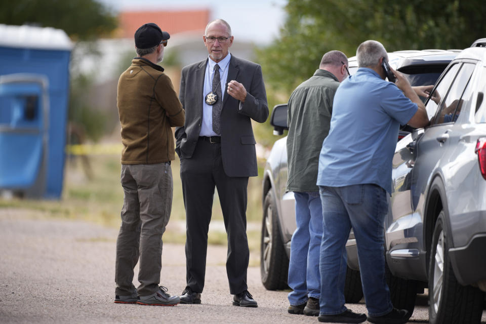Fremont County, Colo., coroner Randy Keller, second from left, meets with fellow authorities outside a closed funeral home where 115 bodies have been stored, Friday, Oct. 6, 2023, in Penrose, Colo. Authorities are investigating the improper storage of human remains at the southern Colorado funeral home that performs "green" burials without embalming chemicals or metal caskets. (AP Photo/David Zalubowski)